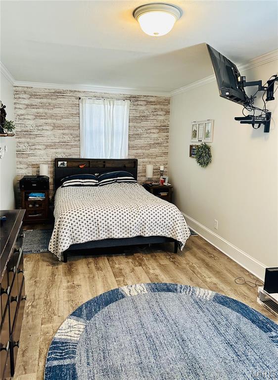 125 Hull Ave, Saint Louis, MO 63119 - bedroom featuring crown molding, baseboards, wood finished floors, and wooden walls
