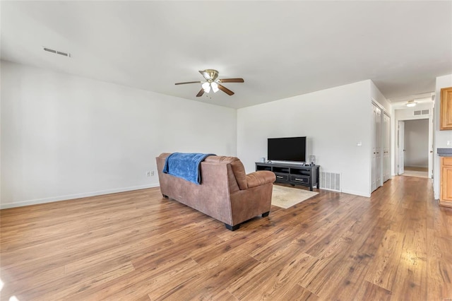 living area with a ceiling fan, light wood finished floors, and baseboards