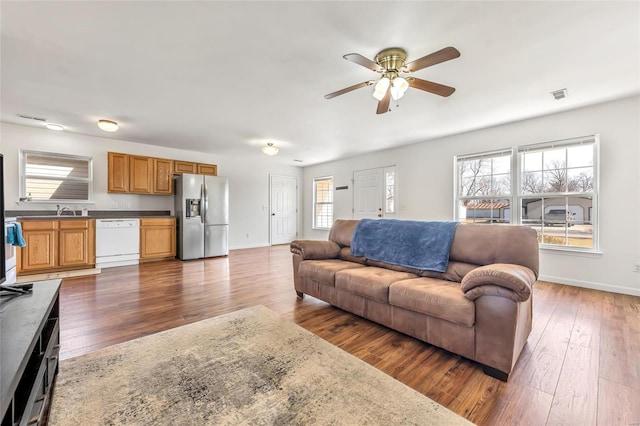 living room featuring dark wood-style flooring, ceiling fan, and baseboards