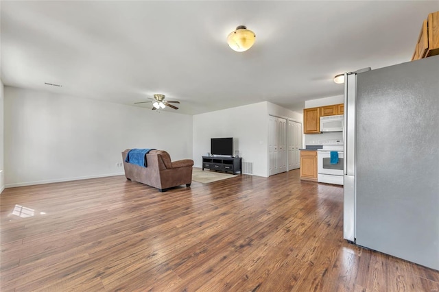 unfurnished living room with ceiling fan, wood finished floors, and baseboards