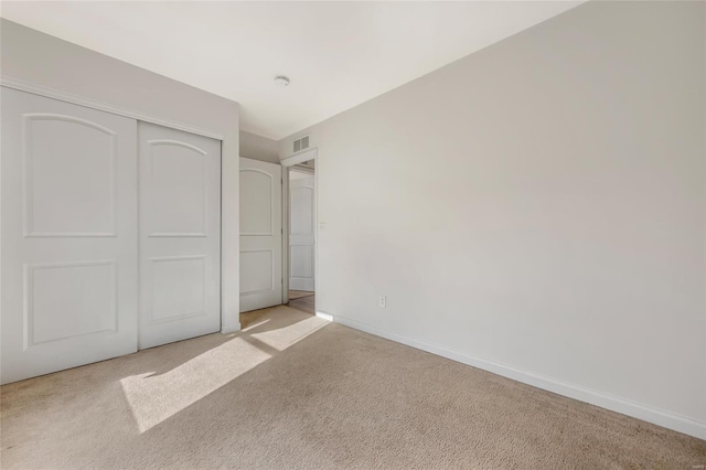 unfurnished bedroom featuring light carpet, baseboards, and a closet