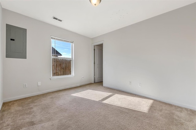 spare room with electric panel, light carpet, and baseboards
