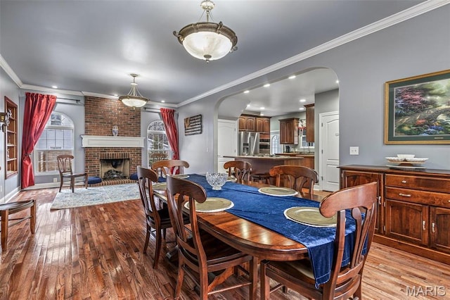 616 W Columbia St, Farmington, MO 63640 - dining space featuring arched walkways, wood finished floors, crown molding, and a brick fireplace