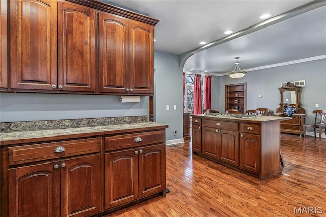 616 W Columbia St, Farmington, MO 63640 - kitchen with arched walkways, wood finished floors, ornamental molding, hanging light fixtures, and a kitchen island