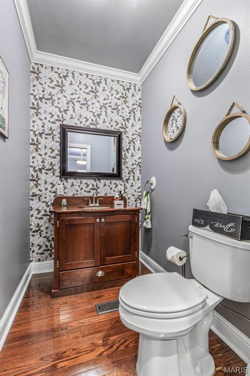 616 W Columbia St, Farmington, MO 63640 - half bath featuring wallpapered walls, ornamental molding, vanity, and wood finished floors