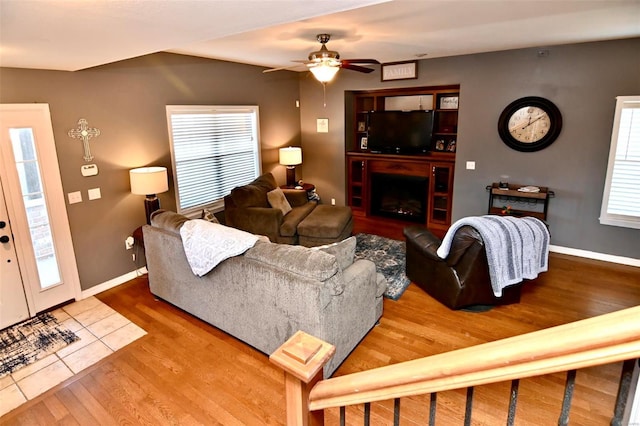 living area with wood finished floors, a ceiling fan, baseboards, and a fireplace