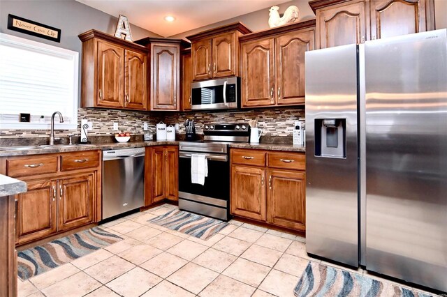 kitchen with appliances with stainless steel finishes, a sink, decorative backsplash, brown cabinetry, and recessed lighting