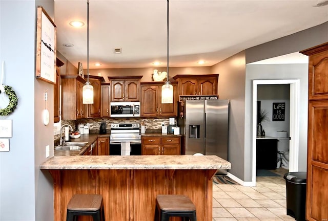 kitchen with stainless steel appliances, a sink, decorative backsplash, a peninsula, and light tile patterned floors