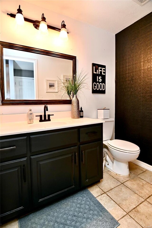 half bathroom with toilet, vanity, and tile patterned flooring