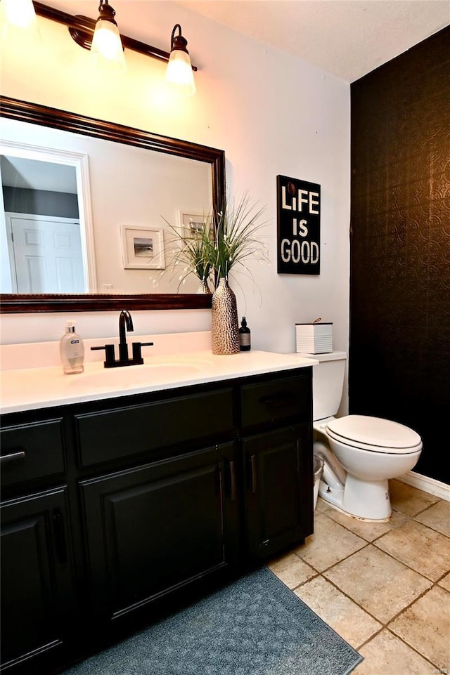 half bath with vanity, toilet, and tile patterned flooring