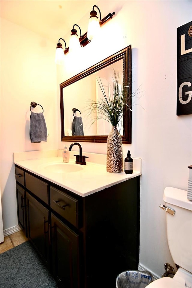 bathroom featuring toilet, vanity, baseboards, and tile patterned floors