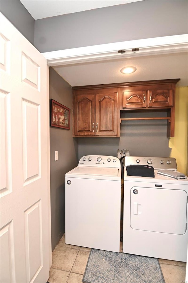 laundry area featuring washing machine and dryer, cabinet space, baseboards, and light stone finish flooring