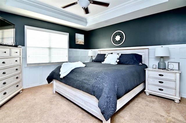 bedroom featuring light carpet, ornamental molding, a decorative wall, a wainscoted wall, and ceiling fan