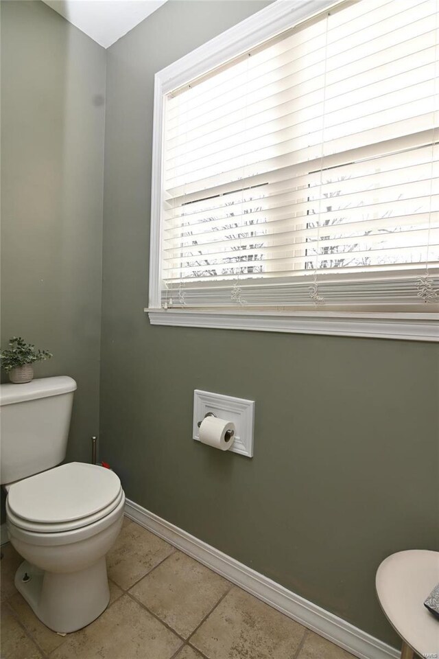 bathroom with baseboards, toilet, and tile patterned flooring