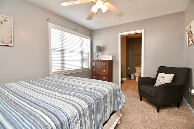 bedroom featuring light carpet, a ceiling fan, baseboards, and ensuite bathroom