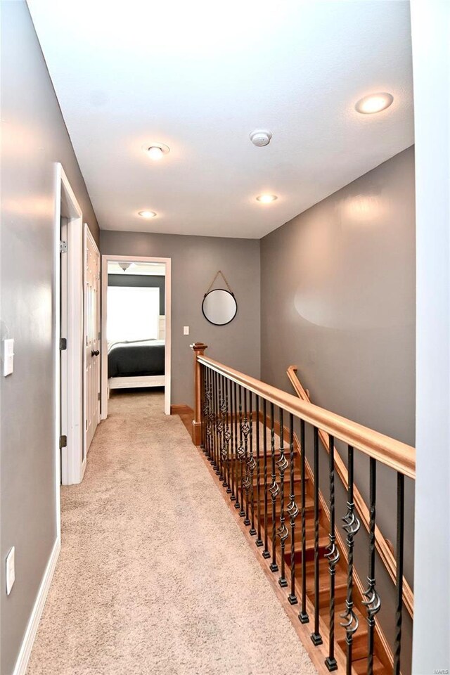 hall featuring an upstairs landing, baseboards, carpet, and recessed lighting