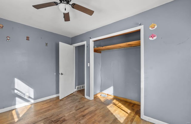 unfurnished bedroom featuring baseboards, wood finished floors, a closet, and ceiling fan