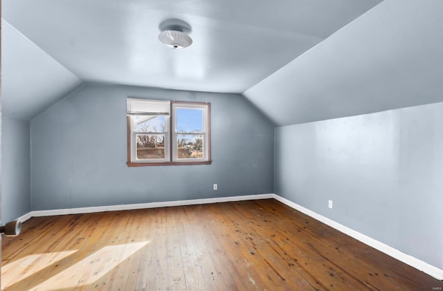 additional living space with hardwood / wood-style floors, lofted ceiling, and baseboards