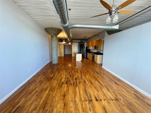 unfurnished living room with dark wood finished floors, baseboards, ceiling fan, and a sink