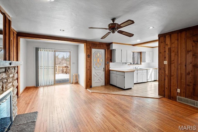 2013 Lily Ave, Saint Louis, MO 63122 - kitchen with light countertops, a ceiling fan, a fireplace, white cabinets, and light wood-style flooring