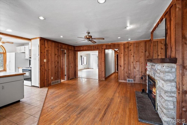 2013 Lily Ave, Saint Louis, MO 63122 - unfurnished living room featuring ceiling fan, a stone fireplace, wood walls, recessed lighting, and light wood-style floors
