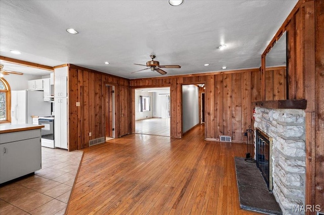 2013 Lily Ave, Saint Louis, MO 63122 - unfurnished living room with a ceiling fan, wooden walls, a stone fireplace, light wood-type flooring, and recessed lighting