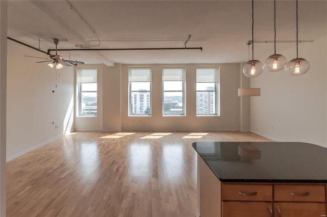 unfurnished living room featuring a ceiling fan, light wood-style floors, and baseboards