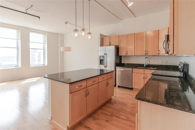kitchen with stainless steel appliances, a sink, light brown cabinets, and light wood-type flooring
