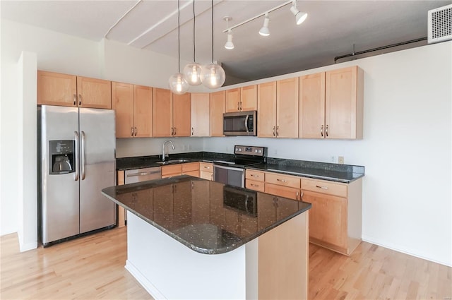 kitchen with appliances with stainless steel finishes, light brown cabinetry, a sink, and light wood-style flooring
