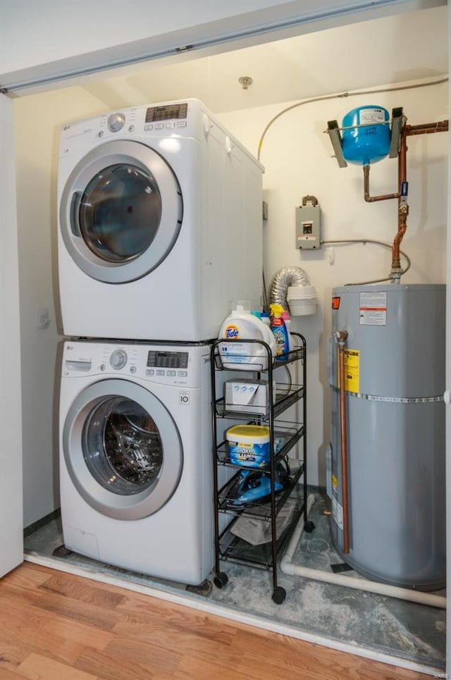 clothes washing area with stacked washer and clothes dryer, gas water heater, and light wood finished floors