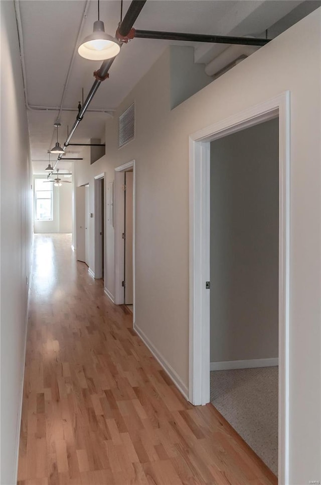 corridor featuring light wood-type flooring and baseboards