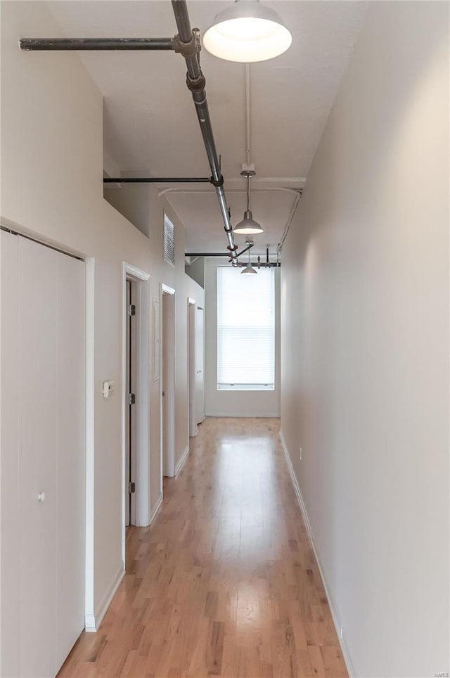 corridor featuring baseboards and light wood-style flooring