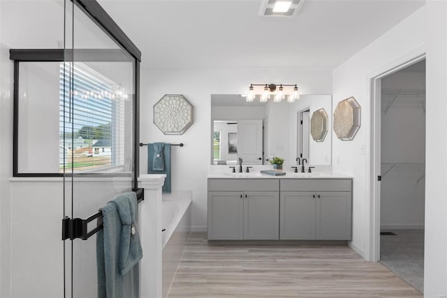 2543 Chukka Dr, Eureka, MO 63025 - bathroom featuring double vanity, a bath, wood finished floors, and a walk in closet