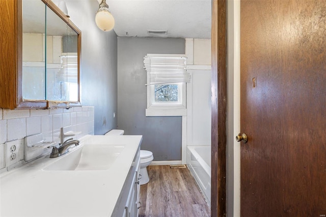 8 Crescent Dr, Viburnum, MO 65566 - bathroom with toilet, wood finished floors, decorative backsplash, vanity, and a bath