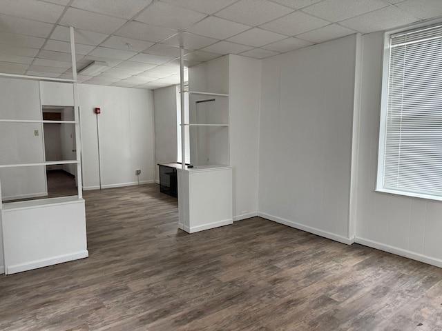 spare room with wood finished floors, a paneled ceiling, and baseboards