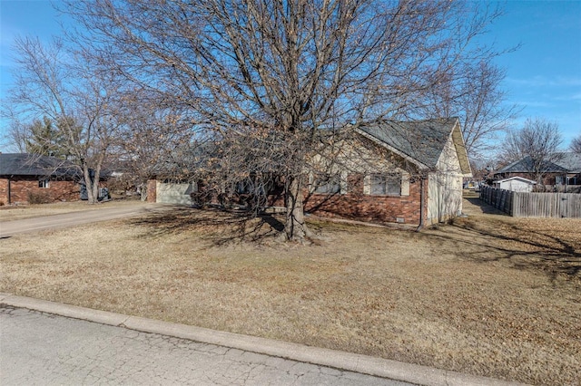 obstructed view of property with fence, driveway, brick siding, and an attached garage