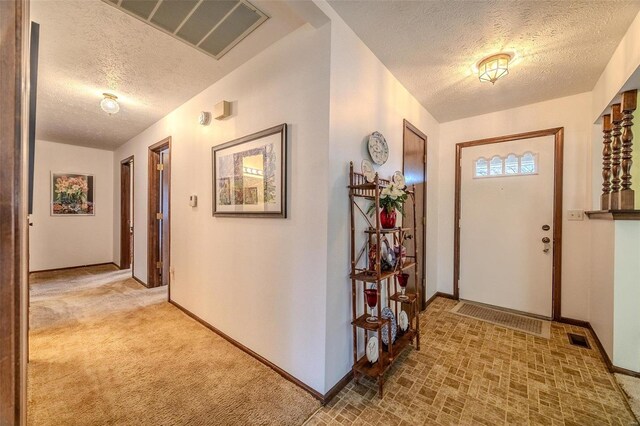entryway featuring a textured ceiling, baseboards, and light carpet