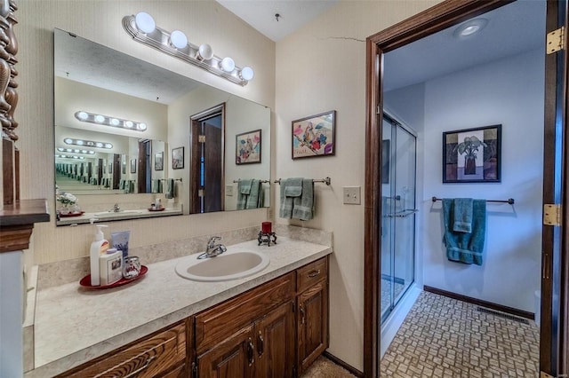bathroom featuring a stall shower, vanity, and baseboards
