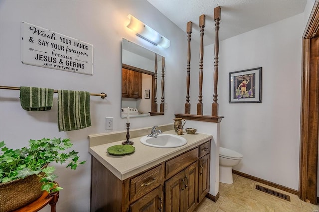 bathroom featuring toilet, vanity, and baseboards