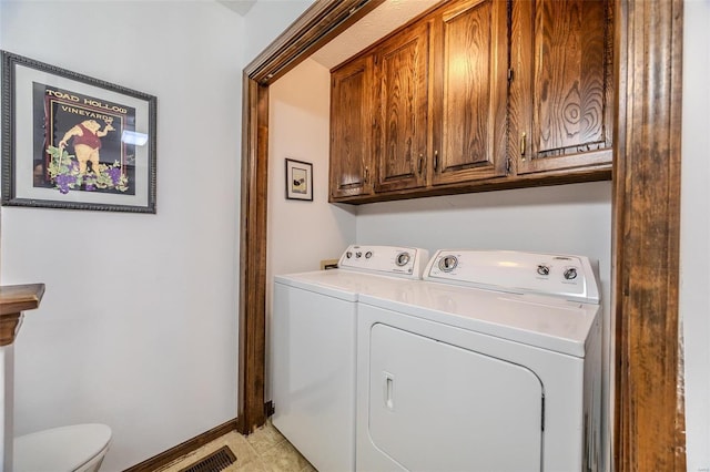clothes washing area with washer and clothes dryer, cabinet space, and baseboards