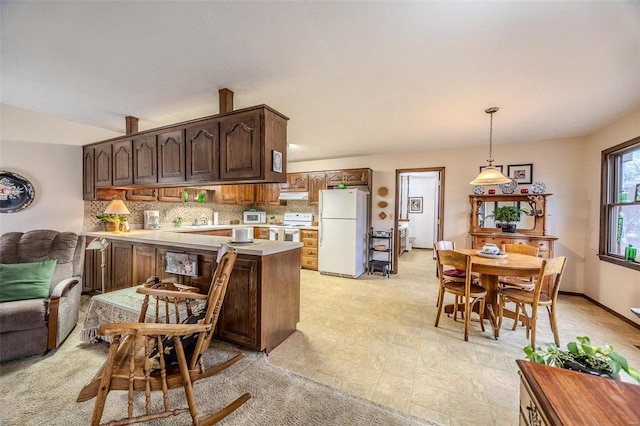 kitchen featuring white appliances, light countertops, a peninsula, backsplash, and dark brown cabinets
