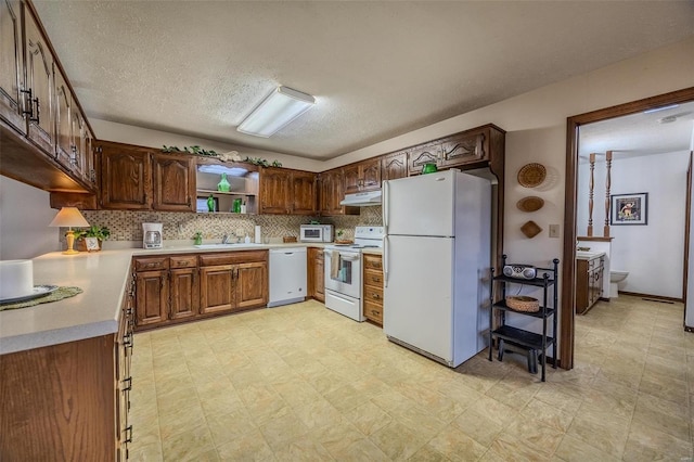 kitchen with white appliances, under cabinet range hood, a sink, open shelves, and decorative backsplash