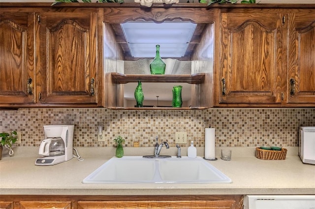 kitchen featuring a sink, dishwasher, light countertops, and decorative backsplash