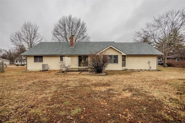 back of house featuring a chimney, central air condition unit, and a yard