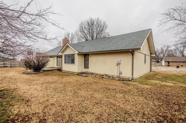 view of side of property with a shingled roof and a chimney