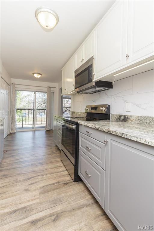 585 Coeur De Royale Dr Unit 201, Saint Louis, MO 63141 - kitchen with stainless steel appliances, light wood-style floors, white cabinets, decorative backsplash, and light stone countertops