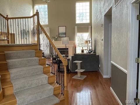 stairway with hardwood / wood-style flooring, a high ceiling, and baseboards