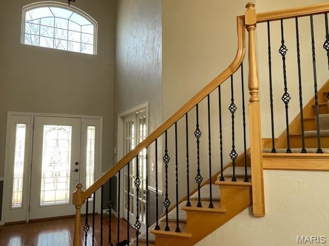 foyer entrance featuring stairway, hardwood / wood-style flooring, and a high ceiling