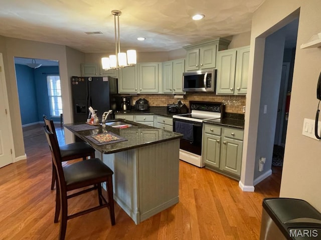 kitchen with electric range, stainless steel microwave, black fridge with ice dispenser, dark countertops, and tasteful backsplash