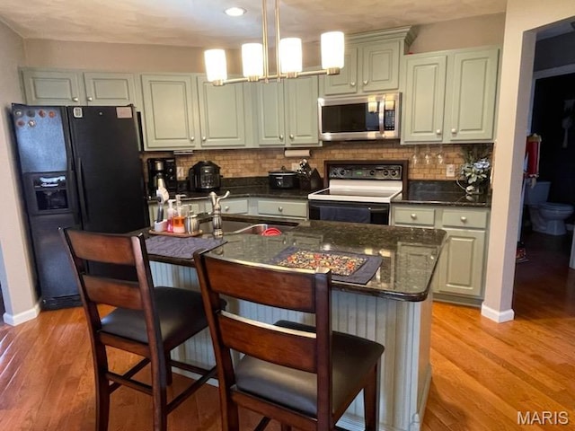 kitchen with stainless steel microwave, range with electric cooktop, black refrigerator with ice dispenser, and decorative backsplash